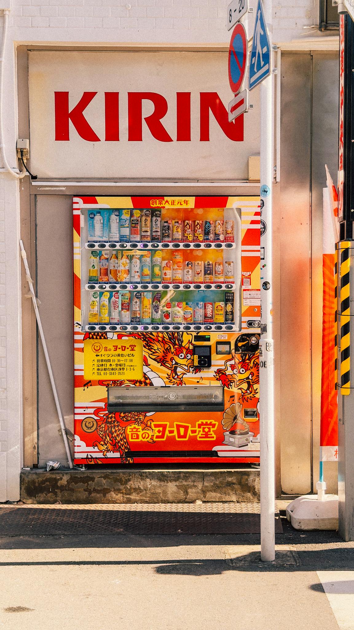 Colorful vending machine under sunlight in Japan, showcasing various drinks with bright signage.