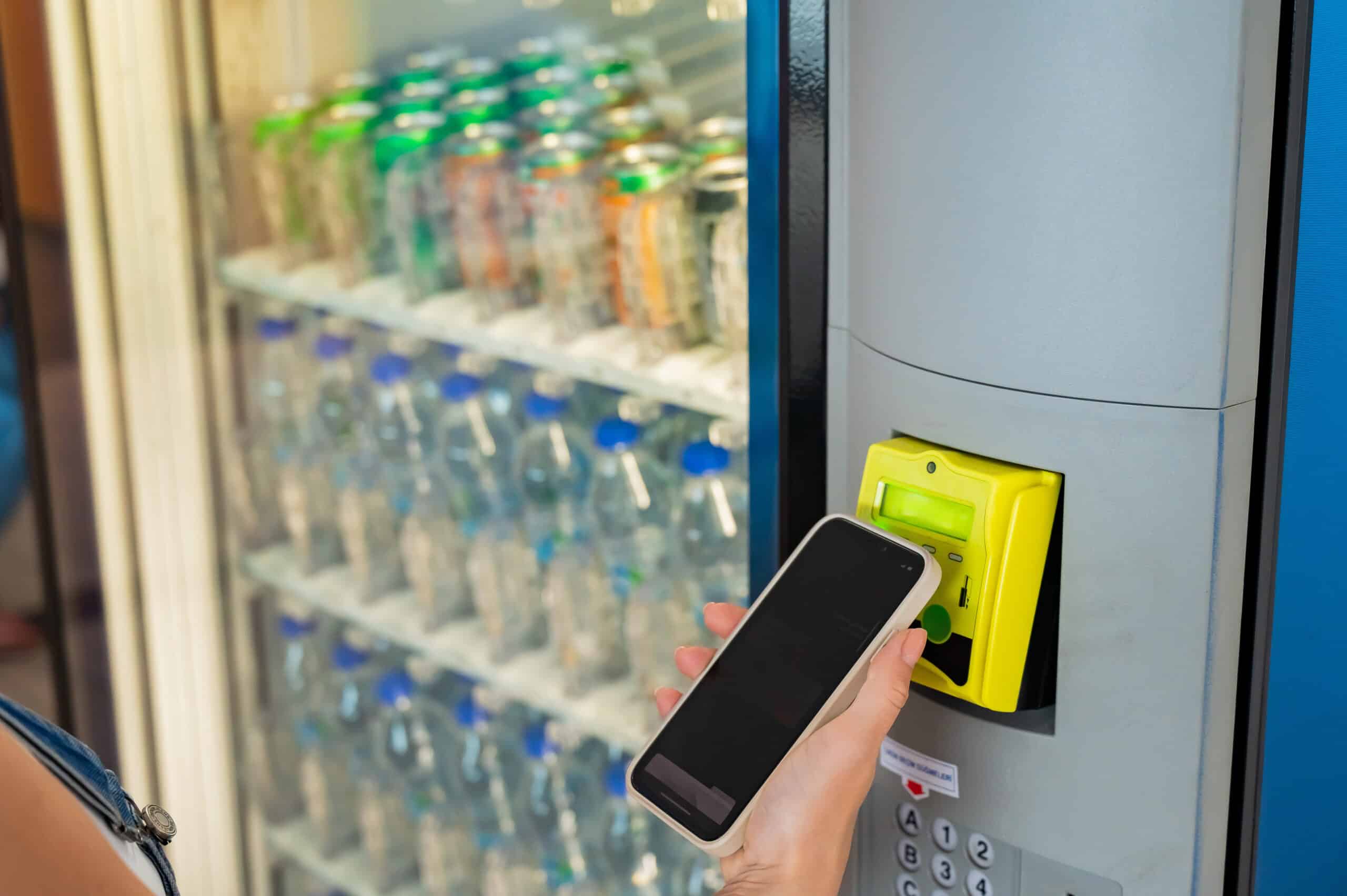 Modern Vending Machine Payment With Mobile Phone. A woman buys a bottle of water from a self-service machine