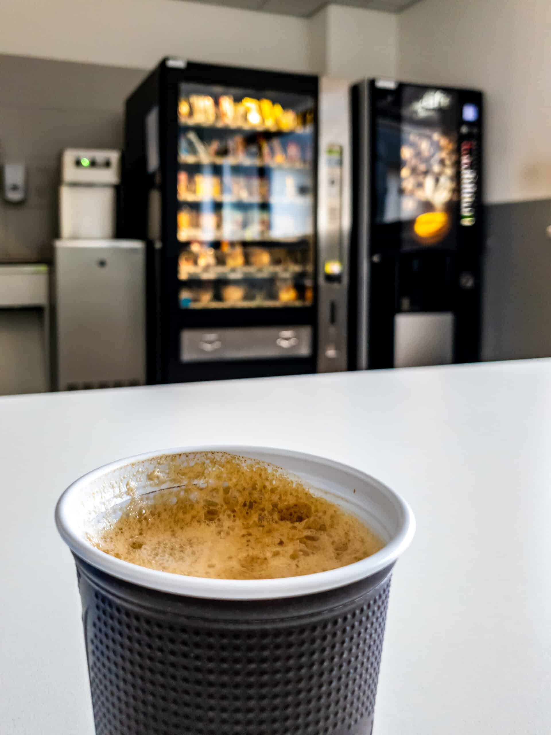 Plastic coffee cup of vending machine standing on table.
