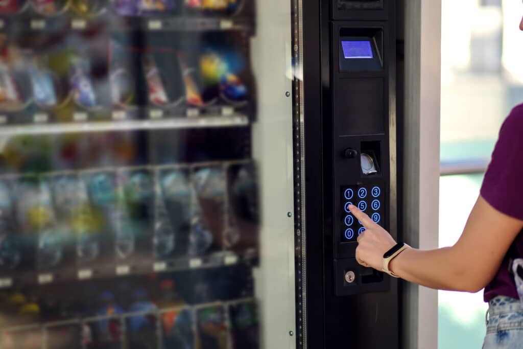 Hand presses button of vending machine pannel. Self-used technology and consumption concept
